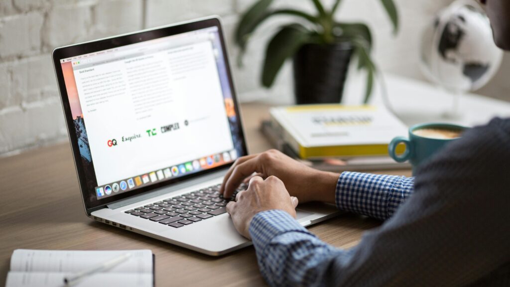 A man working on a laptop at a desk with coffee, showcasing remote work in a modern office setting.